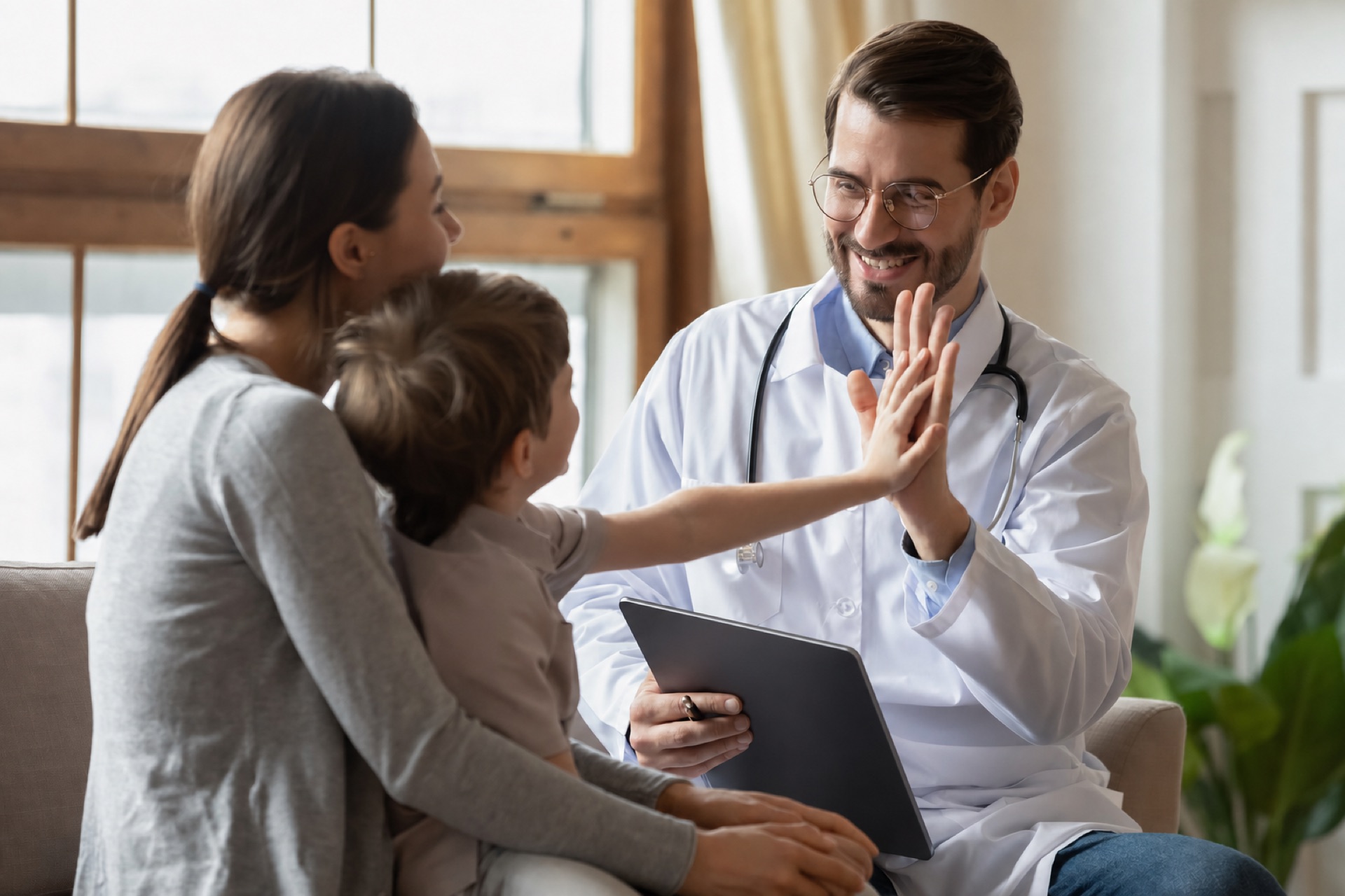 Médico atendiendo a una madre y su hijo, mostrando información en una tablet